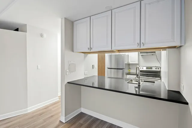 a kitchen with granite countertop a refrigerator sink and cabinets