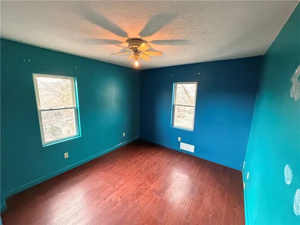 a view of an empty room with window and wooden floor
