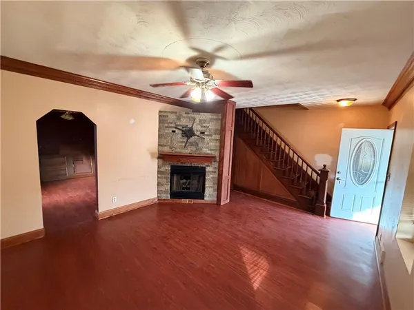a view of an empty room with a fireplace and a chandelier fan