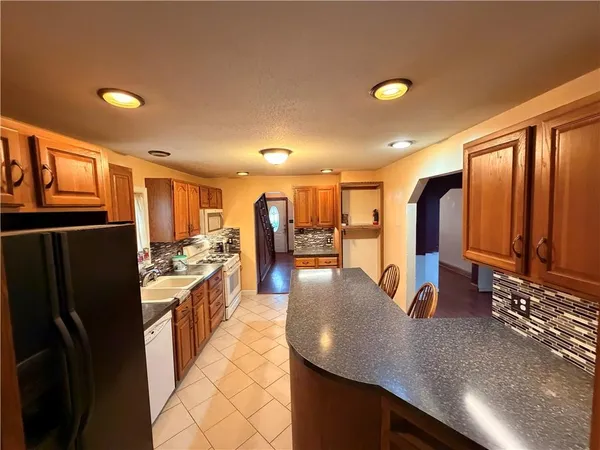 a kitchen with stainless steel appliances granite countertop a refrigerator a oven and a sink with granite countertops