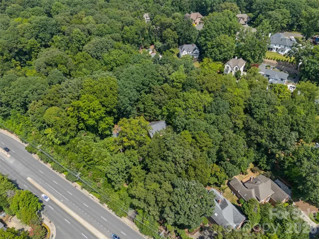 an aerial view of residential house with outdoor space and trees all around