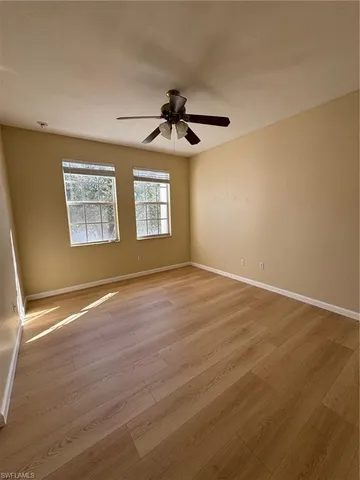 an empty room with a window and a ceiling fan
