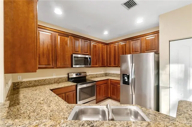 a kitchen with stainless steel appliances granite countertop a stove a sink and a microwave