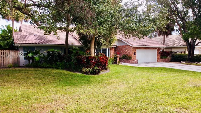a view of a house with a yard garage and a tree
