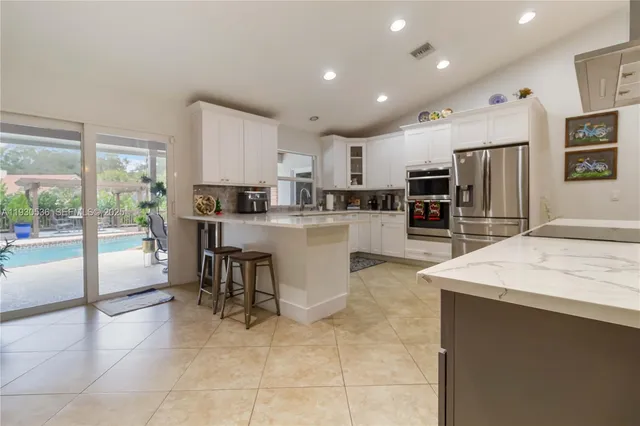 a kitchen with stainless steel appliances kitchen island granite countertop a refrigerator sink and cabinets