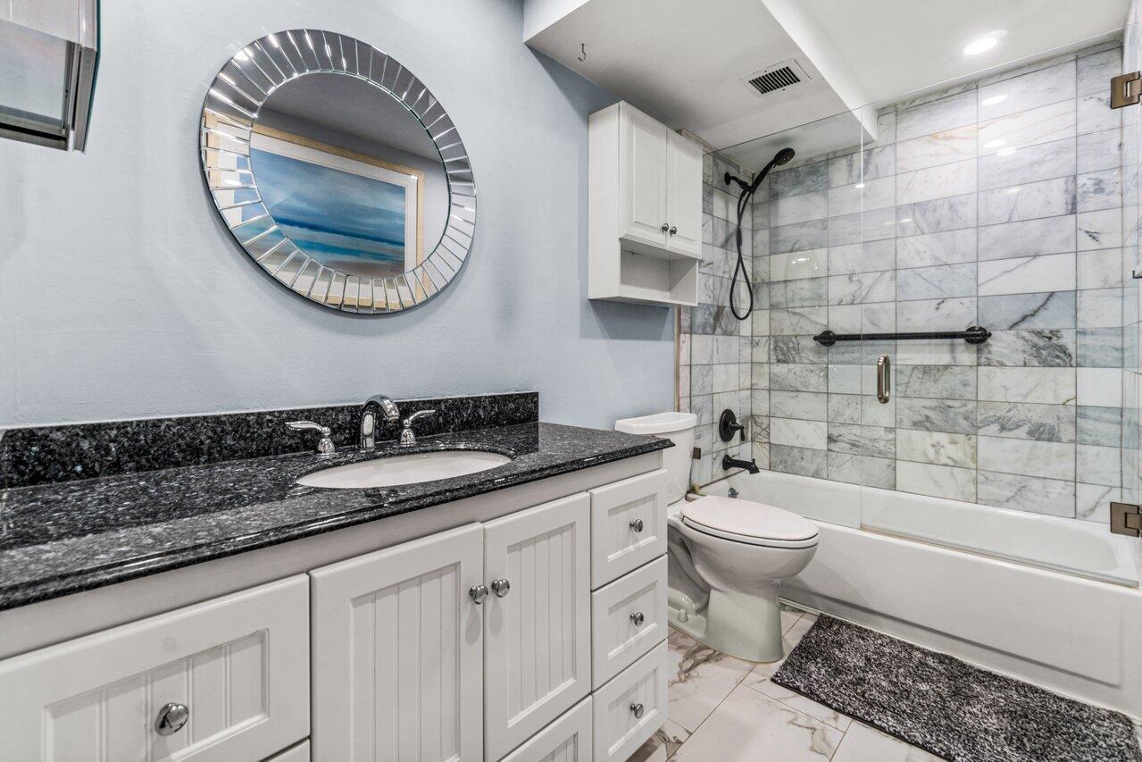 14 Royal Palm Way, Unit 504 Boca Raton, FL 33432 - Photo 16 of 22 a bathroom with a granite countertop toilet a sink and a mirror