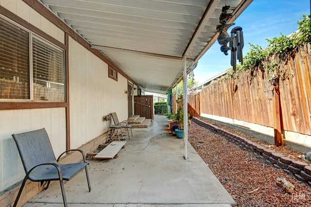a backyard of a house with plants and large tree