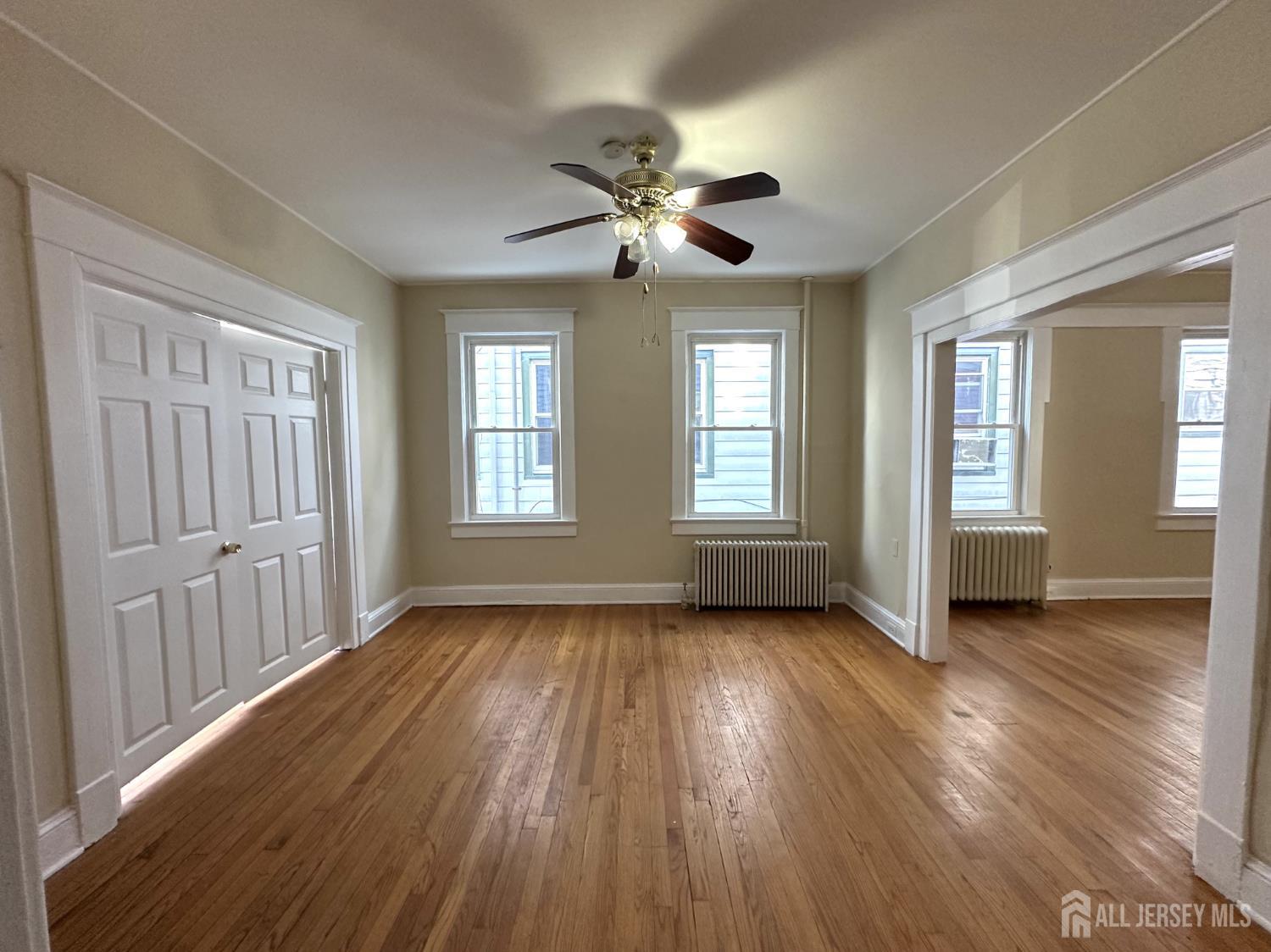 66 Louis Street New Brunswick, NJ 08901 - Photo 2 of 10 a view of empty room with wooden floor and fan