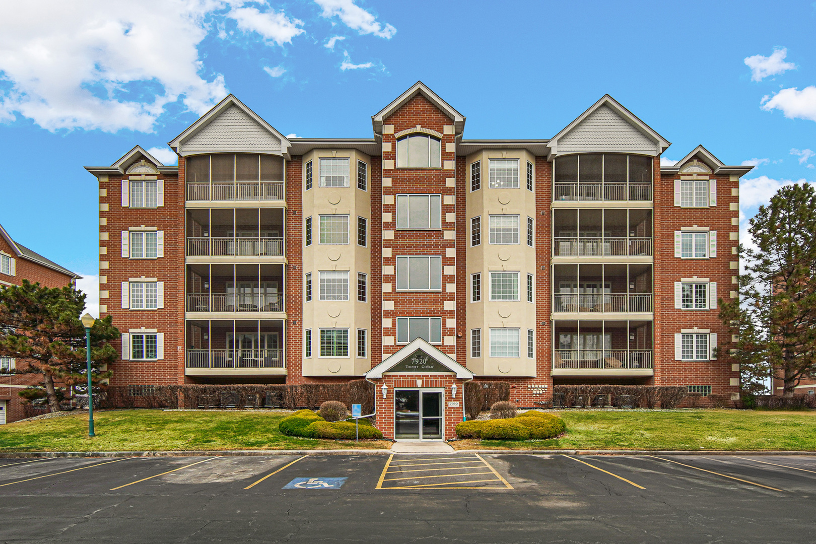a front view of a residential apartment building with a yard and large trees