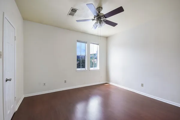 an empty room with wooden floor and windows