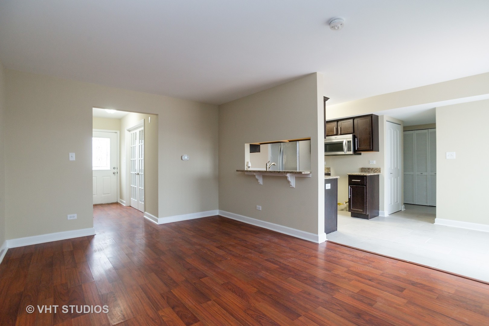 798 Roosevelt Road, Unit 1 Hanover Park, IL 60133 - Photo 3 of 10 an empty room with wooden floor and a kitchen