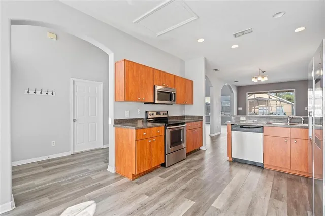 a kitchen with granite countertop wooden floors stainless steel appliances a sink and a window