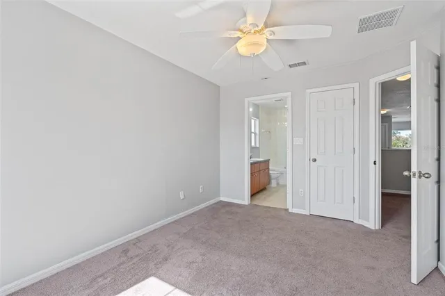 an empty room with a ceiling fan and a bathroom