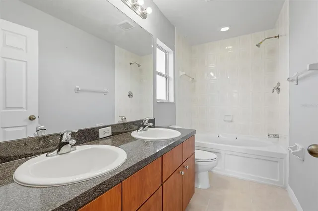 a bathroom with a double vanity sink and mirror with bathtub