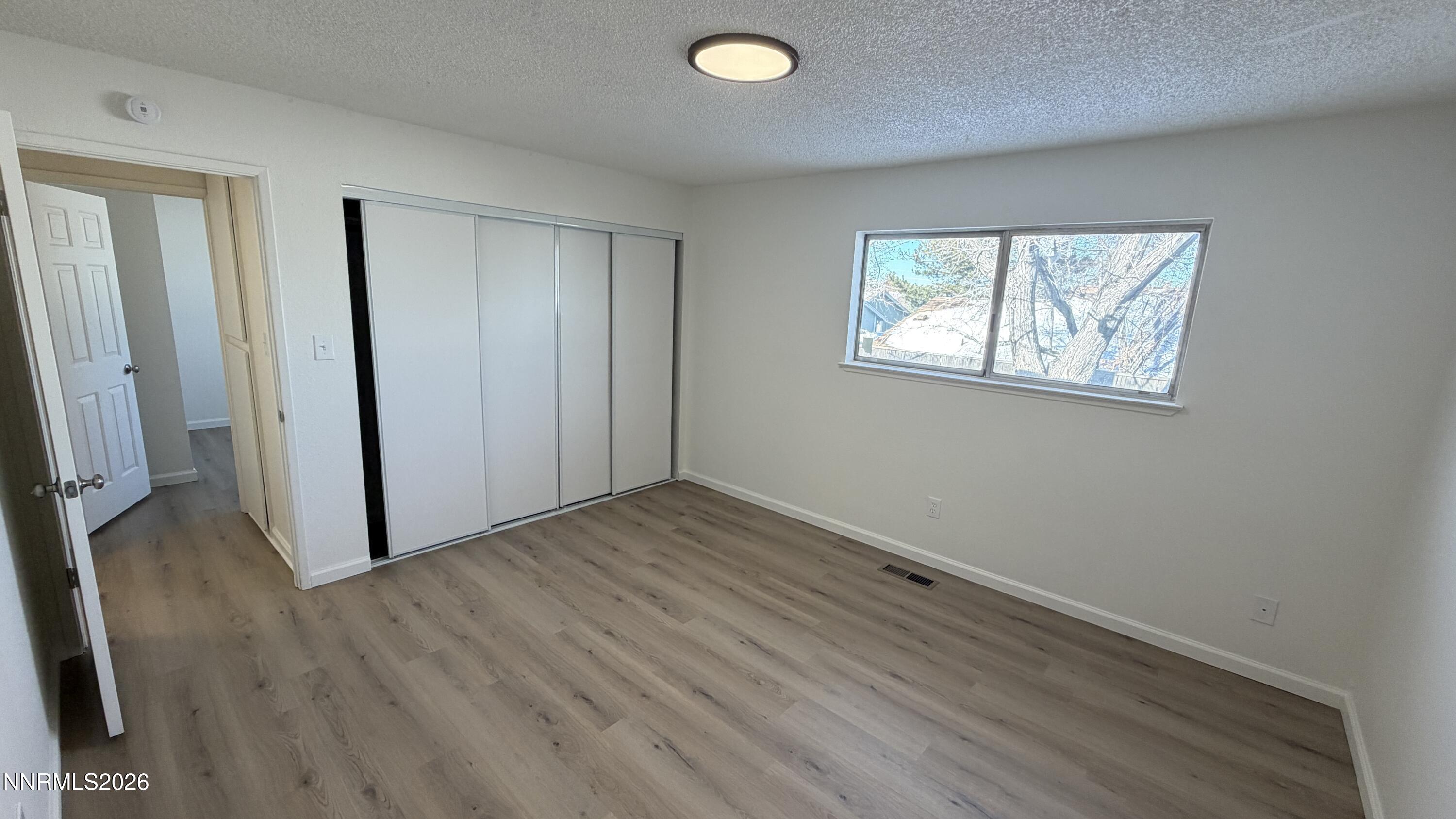 6451 Flower Street Reno, NV 89506 - Photo 7 of 14 an empty room with wooden floor and windows