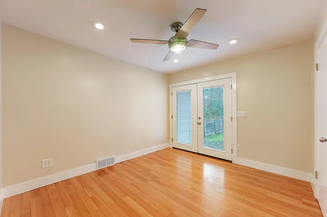 an empty room with wooden floor and windows
