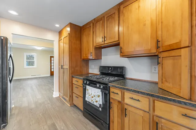 a kitchen with stainless steel appliances granite countertop a refrigerator a stove and a wooden floors