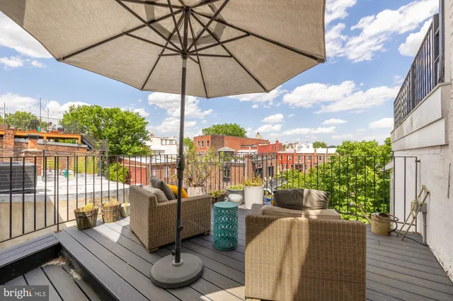 a view of a roof deck with couches under an umbrella
