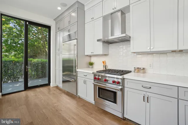 a kitchen with stainless steel appliances white cabinets and a stove top oven