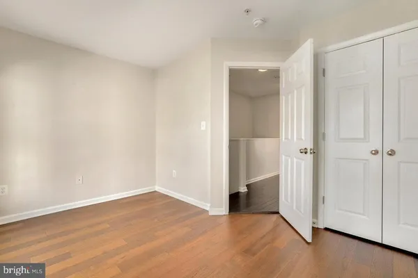 an empty room with wooden floor and closet area