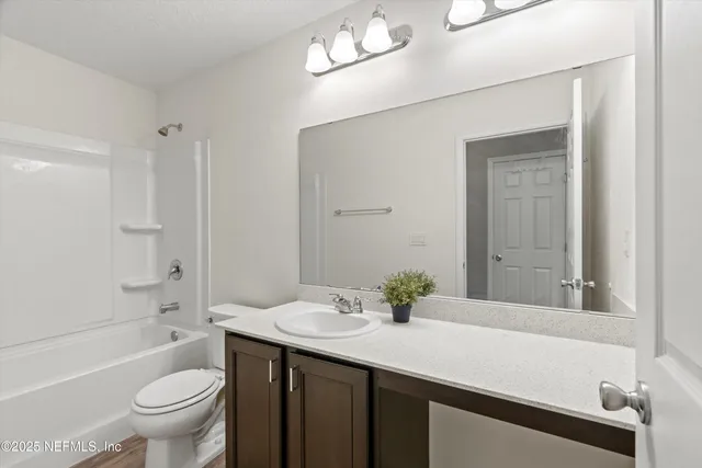 a bathroom with a sink a toilet a mirror and shower