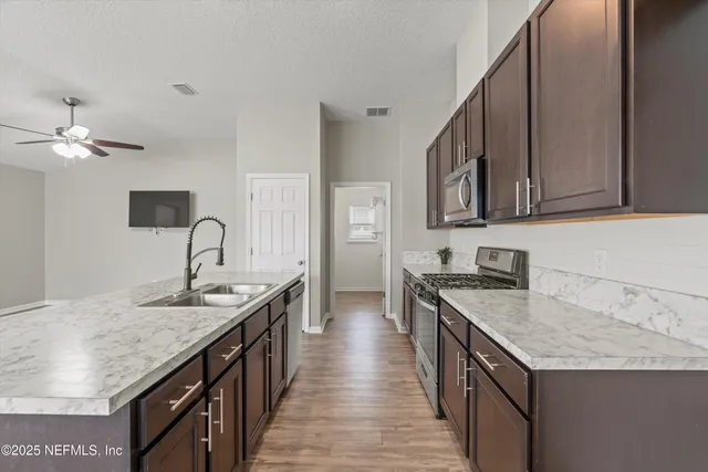 a kitchen with granite countertop stainless steel appliances a sink stove top oven and cabinets