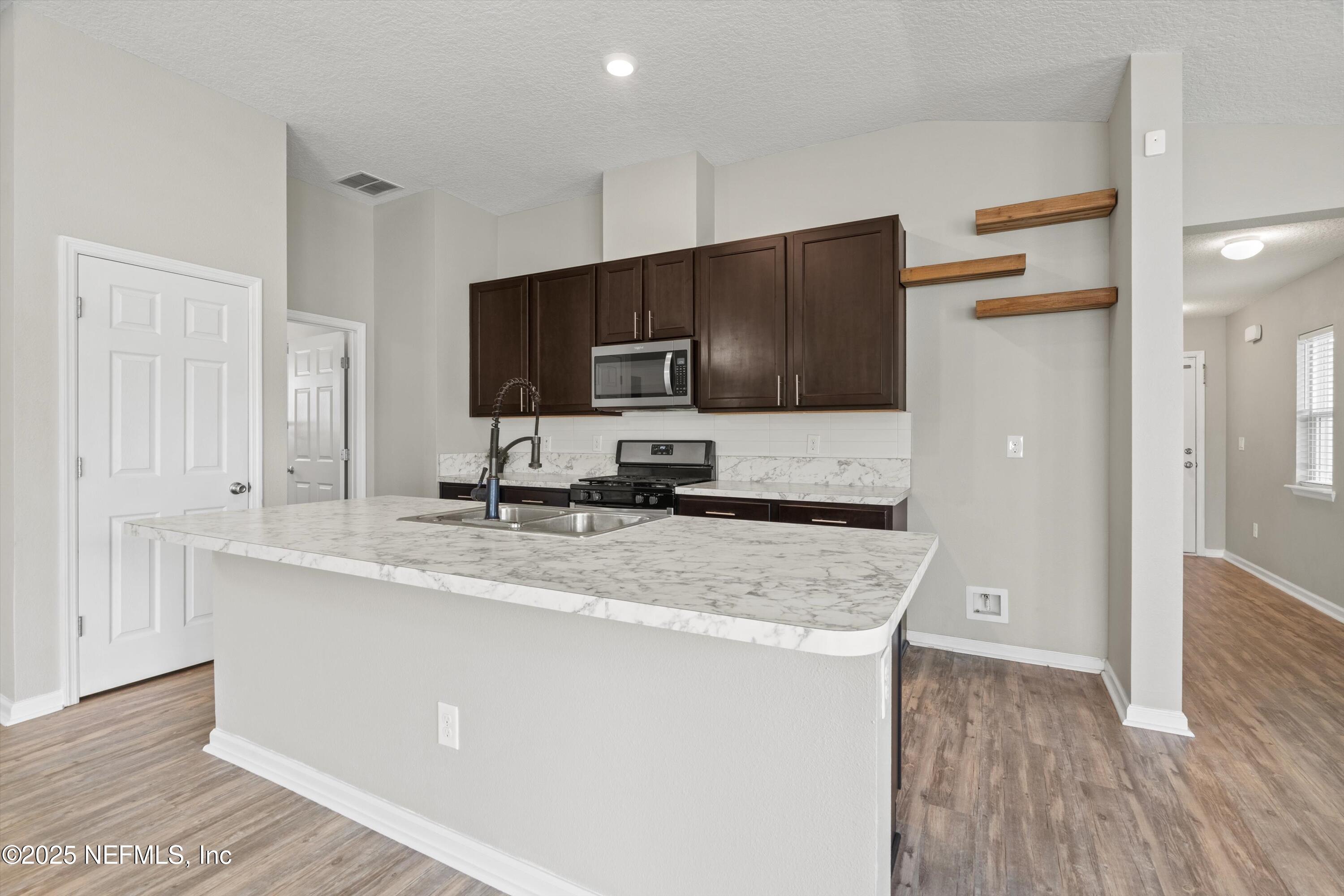 219 Bluejack Lane St. Augustine, FL 32095 - Photo 8 of 44 a kitchen with stainless steel appliances granite countertop a sink refrigerator and microwave