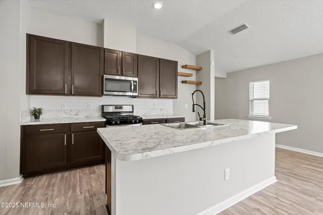 a kitchen with granite countertop a sink stove and microwave