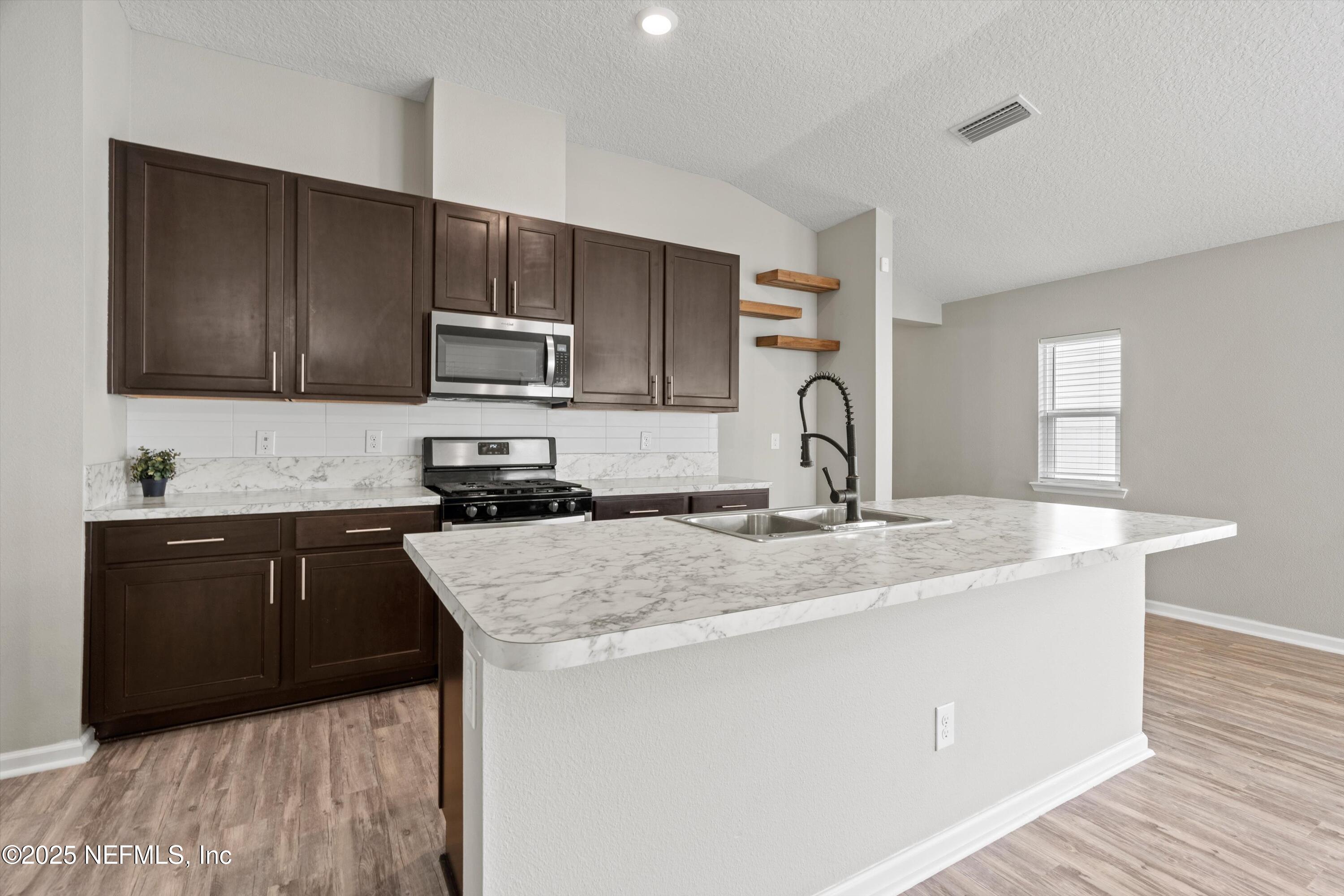 219 Bluejack Lane St. Augustine, FL 32095 - Photo 9 of 44 a kitchen with granite countertop a sink stove and microwave
