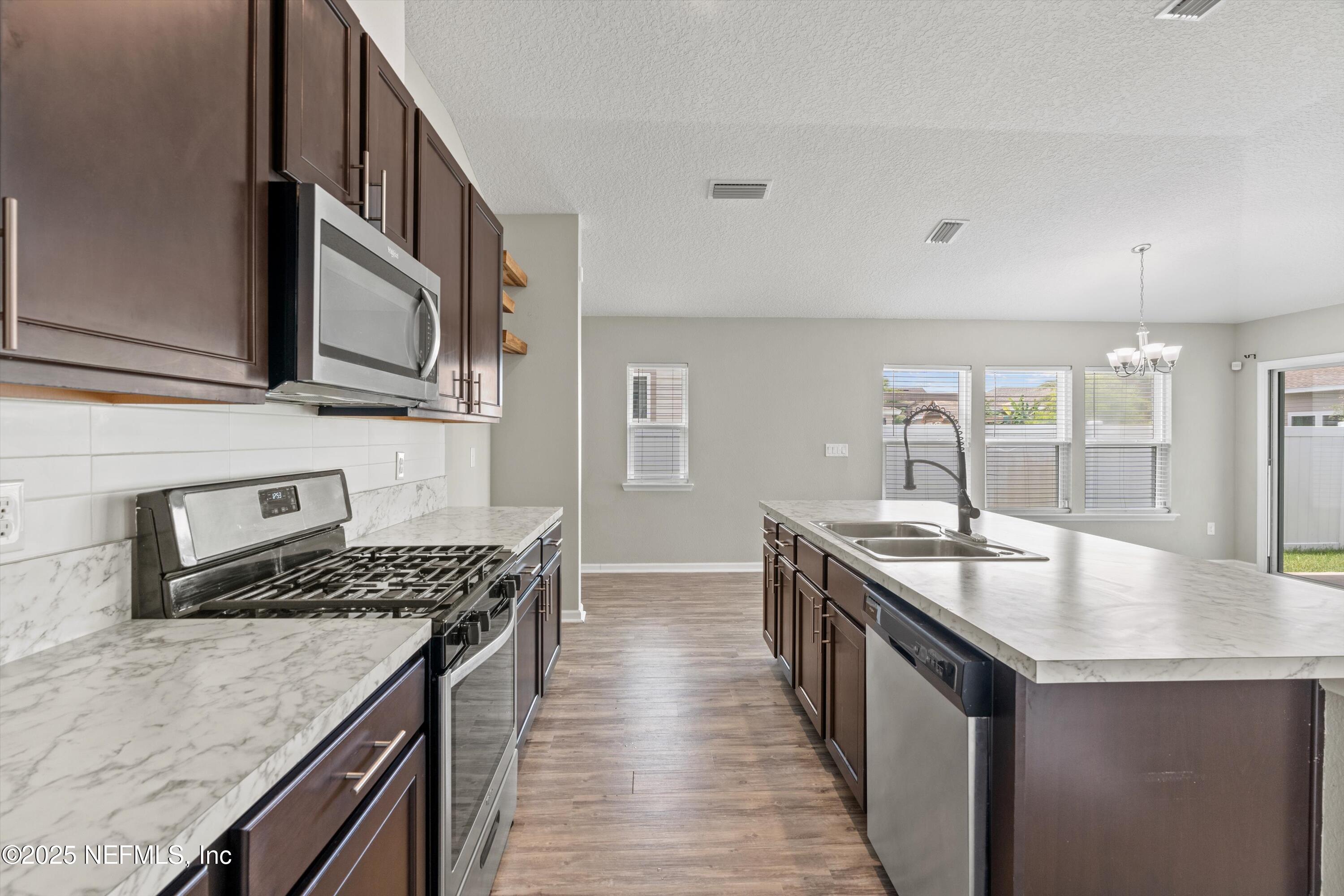 219 Bluejack Lane St. Augustine, FL 32095 - Photo 10 of 44 a kitchen with granite countertop stainless steel appliances a sink stove and cabinets