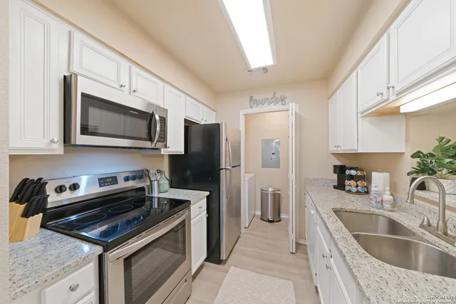 a kitchen with stainless steel appliances a stove a sink a refrigerator a microwave oven cabinets and a counter top space