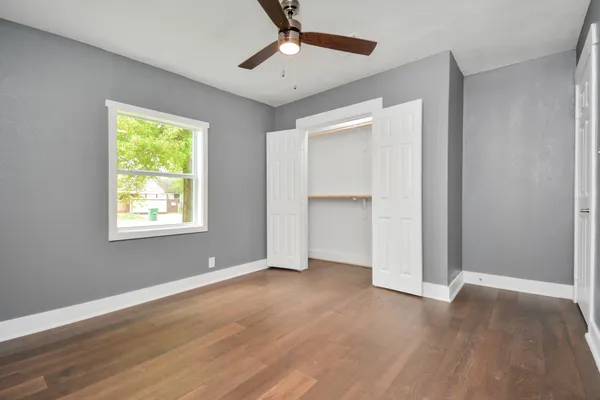 a view of an empty room with a window and wooden floor