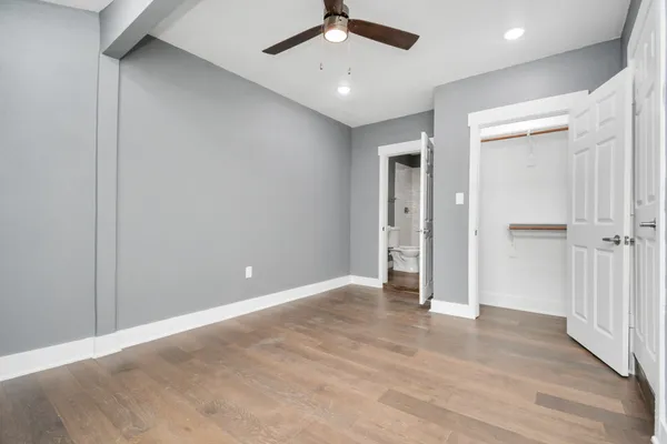 an empty room with wooden floor and ceiling fan