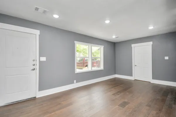 an empty room with wooden floor and windows