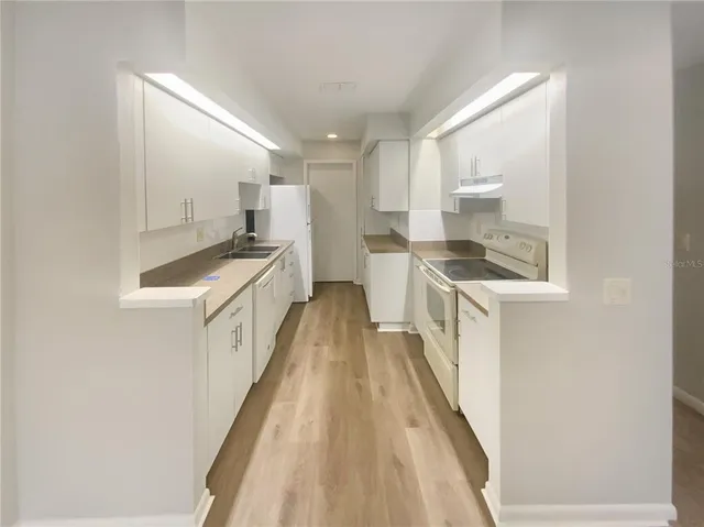 a kitchen with a sink and wooden floor