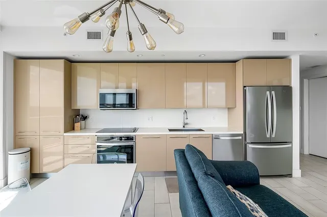 a kitchen with stainless steel appliances granite countertop a refrigerator a sink dishwasher a stove and white cabinets with wooden floor