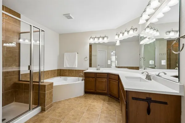 a spacious bathroom with a tub sink shower and mirror