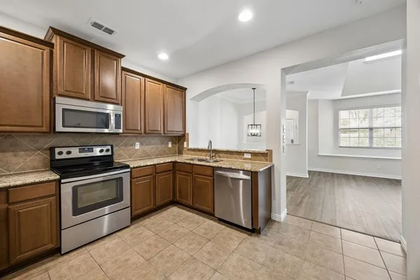 a kitchen with stainless steel appliances granite countertop a stove top oven a sink dishwasher and a refrigerator
