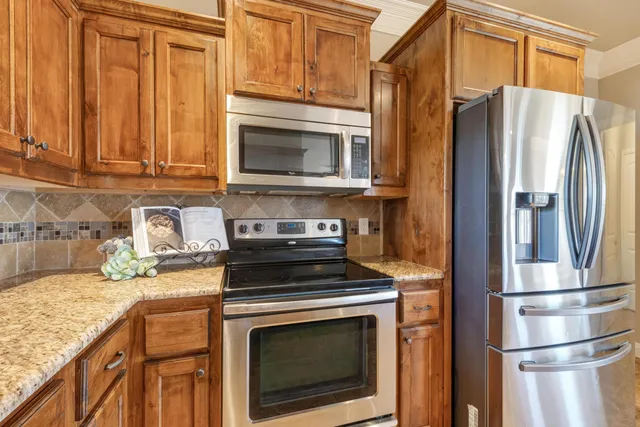 a kitchen with granite countertop a stove microwave and refrigerator