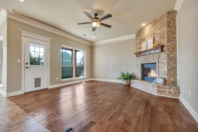 a view of an empty room with wooden floor and a fireplace
