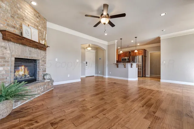 a view of a livingroom with a fireplace a ceiling fan and kitchen view
