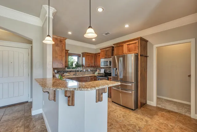 a kitchen with stainless steel appliances granite countertop a refrigerator a sink and a stove