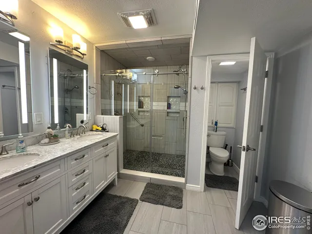 a bathroom with a double vanity sink toilet and shower