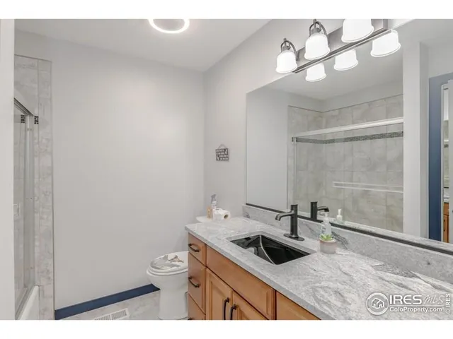 a bathroom with a granite countertop sink a toilet and a mirror
