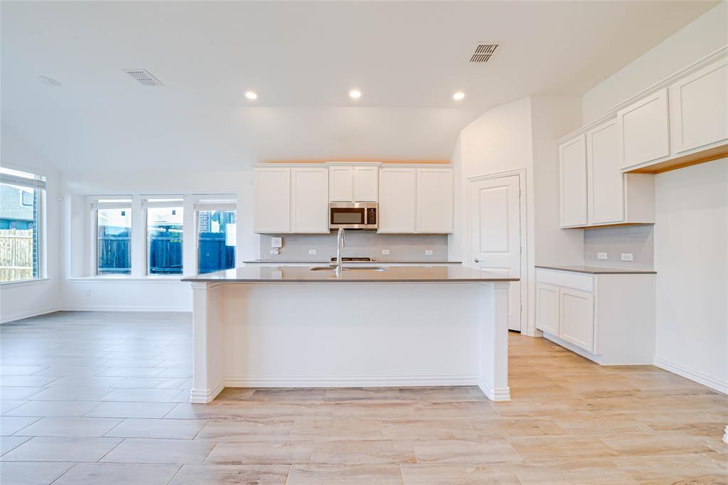 3420 Prairie Place McKinney, TX 75071 - Photo 8 of 37 a large kitchen with granite countertop a stove a sink a refrigerator and white cabinets with wooden floor