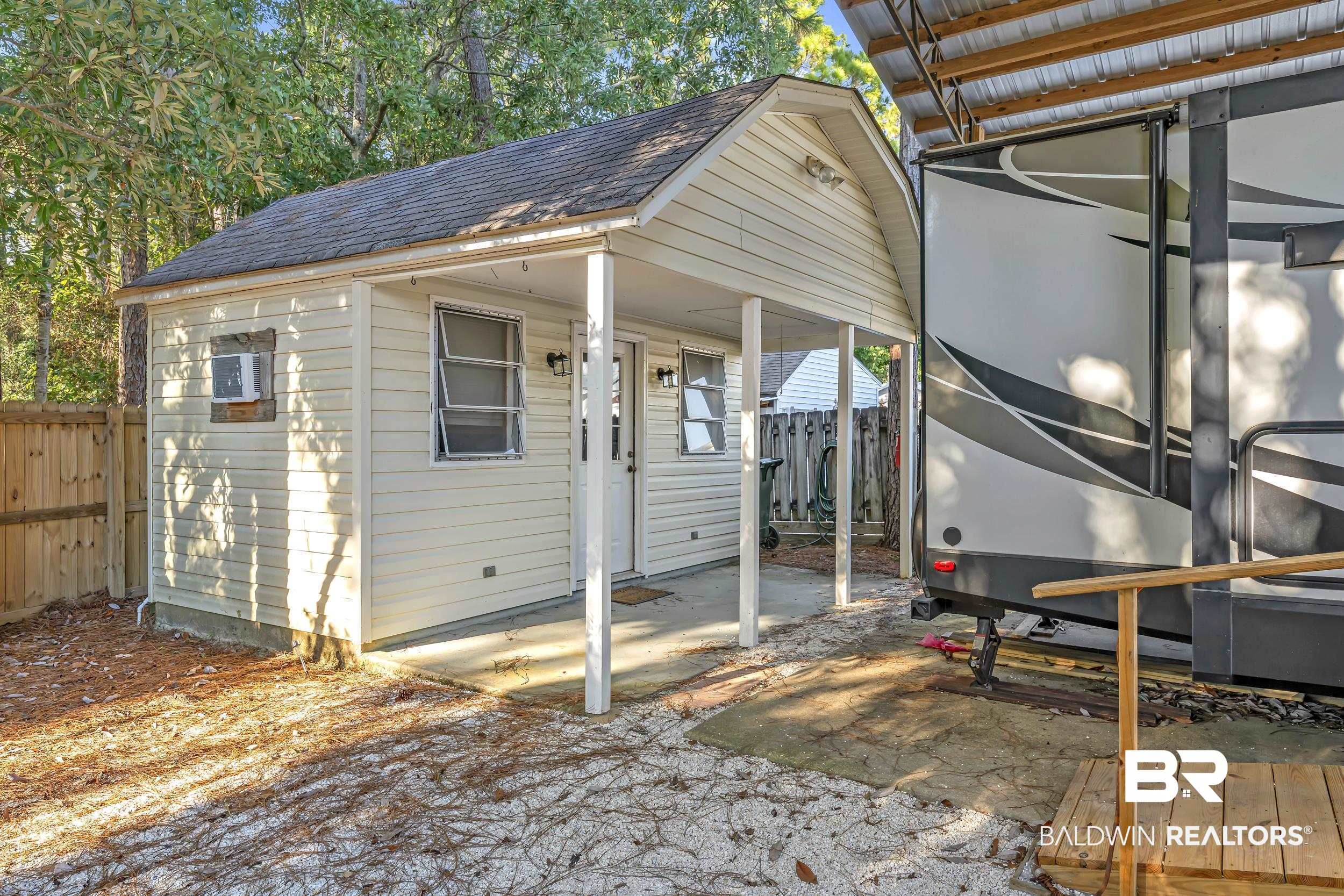 182 Defuniak Loop Lillian, AL 36549 - Photo 9 of 21 Exterior space featuring roof with shingles, an outdoor structure, and a patio area