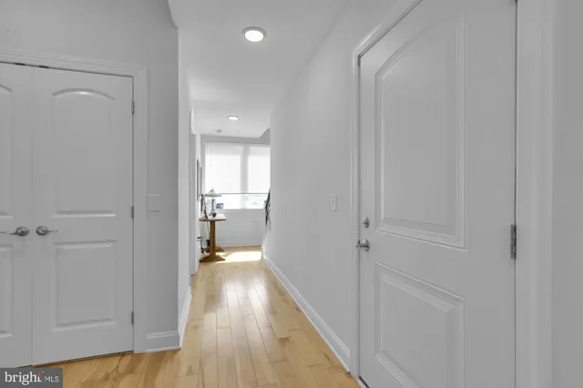 a view of a hallway with wooden floor and a bathroom