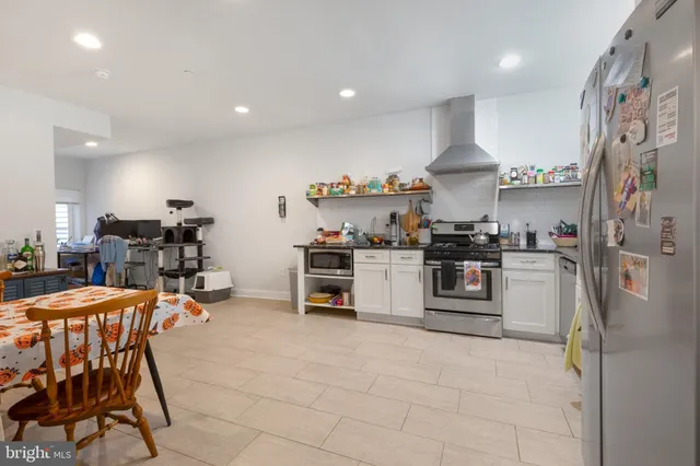 a kitchen with stainless steel appliances a table and chairs in it