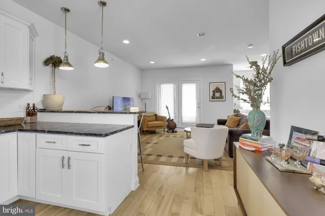 a living room with stainless steel appliances granite countertop couches a fireplace a flat screen tv and a dining table with wooden floor