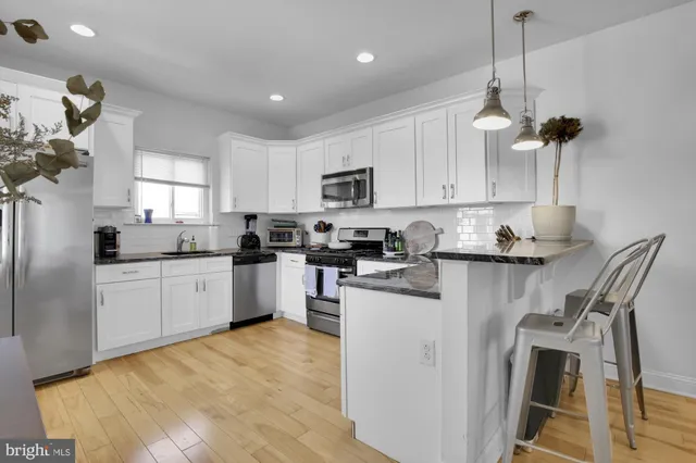 a kitchen with stainless steel appliances granite countertop a sink a stove a refrigerator cabinets and a window